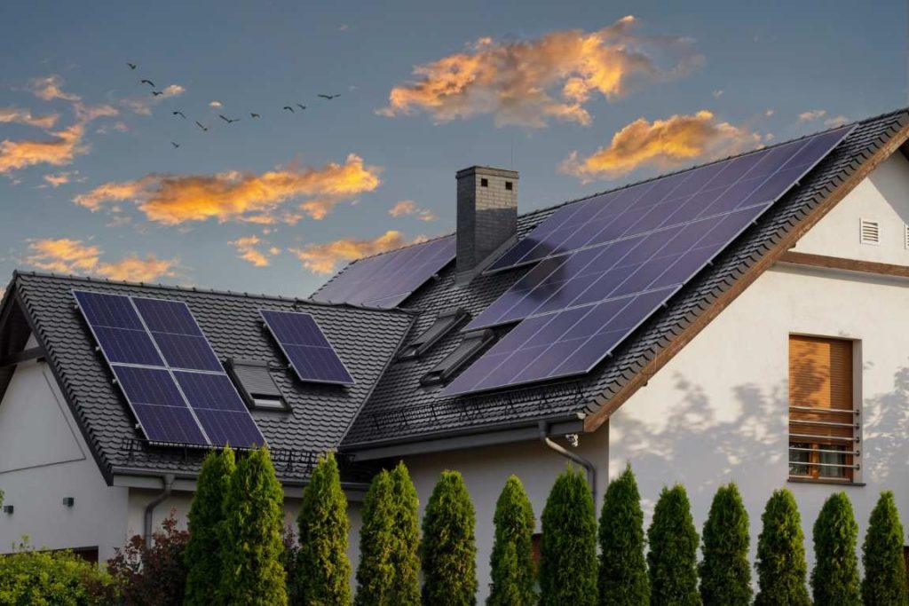 Modern House With Blue Solar Panels On The Roof. End Of The Day, Sunset